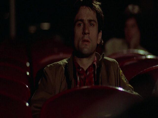 Robert De Niro sentado en una sala de cine en Taxi Driver de Martin Scorsese